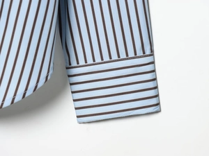 Macro shot of striped cotton shirt cuffs with detailed stitching and blue-brown fabric