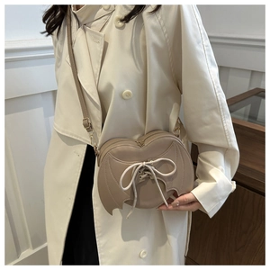 Detailed view of khaki heart-shaped bat wing bag with lace-up bow and leather stitching
