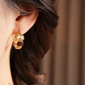 Close-up of vintage geometric earrings with champagne and brown stones on gold metal