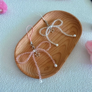 Close-up of handmade beaded phone charms with crystal bows and metallic star pendants