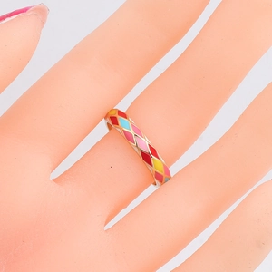 Detailed close-up of colorful enamel geometric ring with diamond patterns on model finger