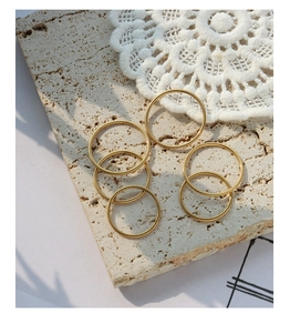 Detailed view of six minimalist gold stainless steel rings on a natural stone surface