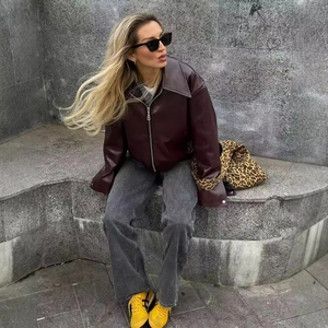 Giacca in pelle viola scuro con scollo quadrato abbinata a jeans grigi in stile street