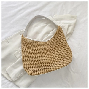 Detailed view of hand-woven straw bag with white trim and wide shoulder strap