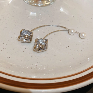 Close-up of silver flower earrings with white pearls on a ceramic tray display