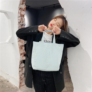 Primer plano de un bolso tote de lona a cuadros azules y blancos con diseño minimalista