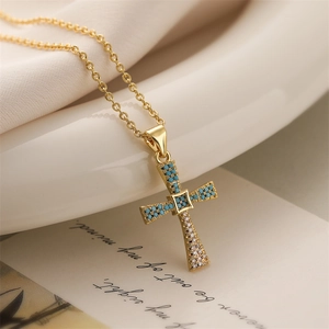 Close-up of gold-plated cross pendant with turquoise beads and zircon on vintage paper