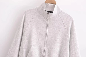 Close-up of light grey zip-up sweatshirt with stand collar and metallic zipper detail