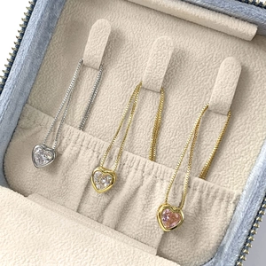 Drei elegante Herz-Halsketten in Silber und Gold, präsentiert in einer Samt-Schmuckschatulle
