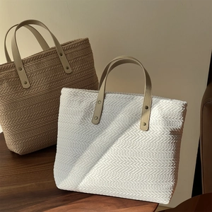 Detail of herringbone woven tote bags in beige and white with leather handles
