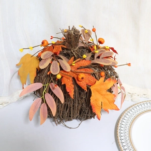 Detail of woven rattan pumpkin base with autumn maple leaves and orange berries