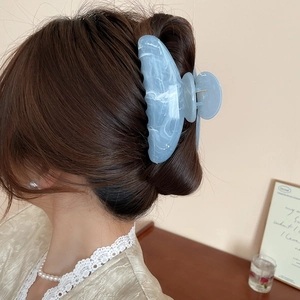 Pince à cheveux en acétate marbré bleu portée avec style par un mannequin