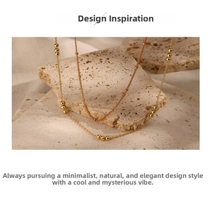 Macro detail of minimalist gold chain necklace with polished beads on a stone pedestal