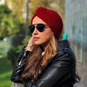 Close-up of a deep red knit turban hat featuring a chunky cross-knot texture