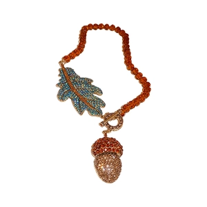Collier pomme de pin en cristal ambre avec pendentif feuille dorée serti de diamants sur blanc