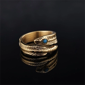 Golden stainless steel feather ring with turquoise stone inlay on black reflective surface
