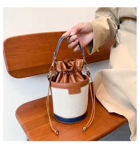 Detail of canvas bucket bag with leather patchwork, drawstring closure and metal clasp