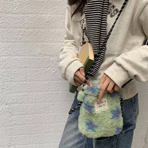Detail of green plush crossbody bag with floral pattern and braided rope strap