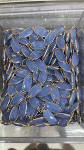 Bulk blue oval faceted crystal pendants with gold edges in a clear container