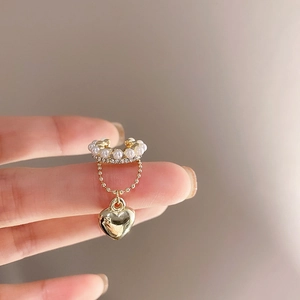 Macro view of gold bow cuff earring with white pearls, zircons and a heart pendant