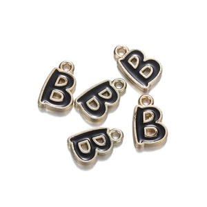 Detail of five gold-plated B-letter charms with black enamel filling on white background