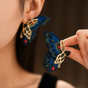 Détail macro de boucles d'oreilles papillon vintage avec broderie bleue et cristaux