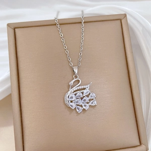 Detailed view of silver swan pendant with sparkling crystals on white silk background
