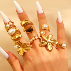 Gold stainless steel ring set with pearls and flower leaf motifs on a warm background