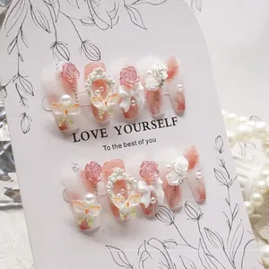 Detailed view of handmade pink press-on nails with 3D resin roses and pearl accents