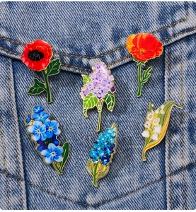 Set of six floral enamel pins on denim jacket showing lily of the valley and lilac details