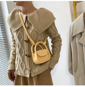 Détail d'un mini sac à main en cuir jaune vif porté sur un pull en maille beige par un mannequin