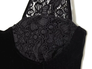 Detailed close-up of the delicate lace and soft velvet fabric texture on the black dress