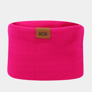 Close-up of pink knitted winter headband with brown leather label embossed with MOM text