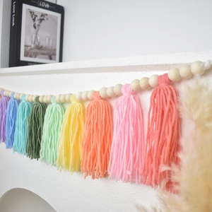 Detail of bohemian wood bead garland with colorful rainbow tassels on a white fireplace