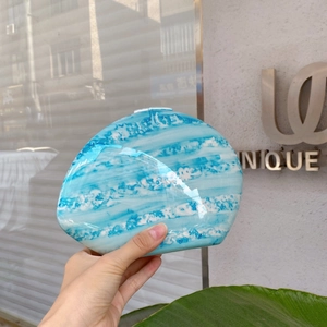 Detail of egg-shaped marble pattern evening clutch with smooth glossy acrylic finish