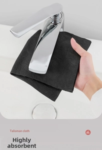 Close-up of thick black microfiber cleaning cloth wiping a chrome faucet with water drops