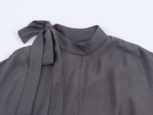 Detail of dark grey high neck blouse with elegant shoulder bow tie and woven fabric texture