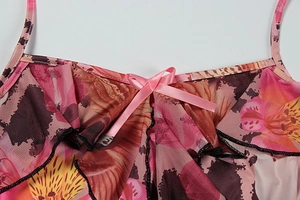 Detailed close-up of floral leopard print mesh fabric with pink satin bow and ruffle trim