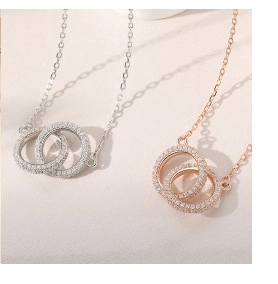 Close-up of interlocking double rings necklace with sparkling crystals in silver and rose gold