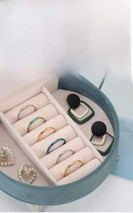 Macro shot of dark green velvet jewelry box with organized ring slots and soft pink lining
