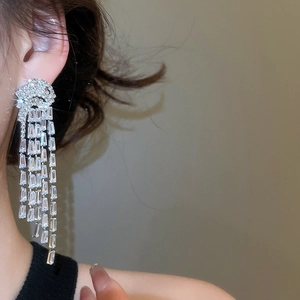 Détail de boucles d'oreilles à pompon en argent avec cristaux de zircon portées