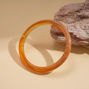 Minimalist amber acrylic geometric round bangle with white marble texture on natural stone