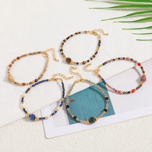 Set of five handmade natural stone beaded bracelets with gold accents on a white background