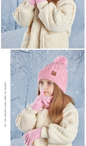 Detail of pink knitted hat, scarf, and gloves set with faux fur pom and leather patch