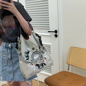 Detail of light gray nylon tote bag with colorful horse embroidery and woven rope handle