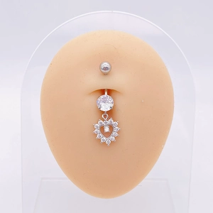 Macro detail of silver heart belly button ring with clear zircons on model skin