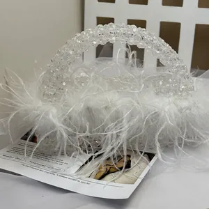 Detail of handcrafted white beaded evening bag with fluffy ostrich feathers on magazine