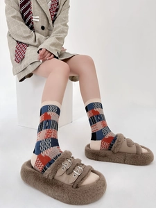 Detail of vintage geometric plaid cotton socks worn with cozy plush slippers and blazer