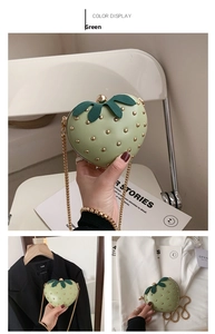 Detail of strawberry-shaped crossbody bag in light green with gold rivet seeds