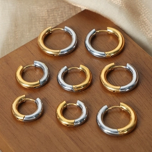 Minimalist two-tone round hoop earrings in mixed gold and silver steel on wooden display
